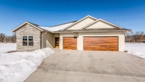 Front view of single story home with rock facade in the snow