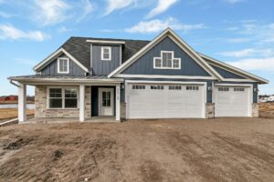 Front view of blue single story home with dirt driveway