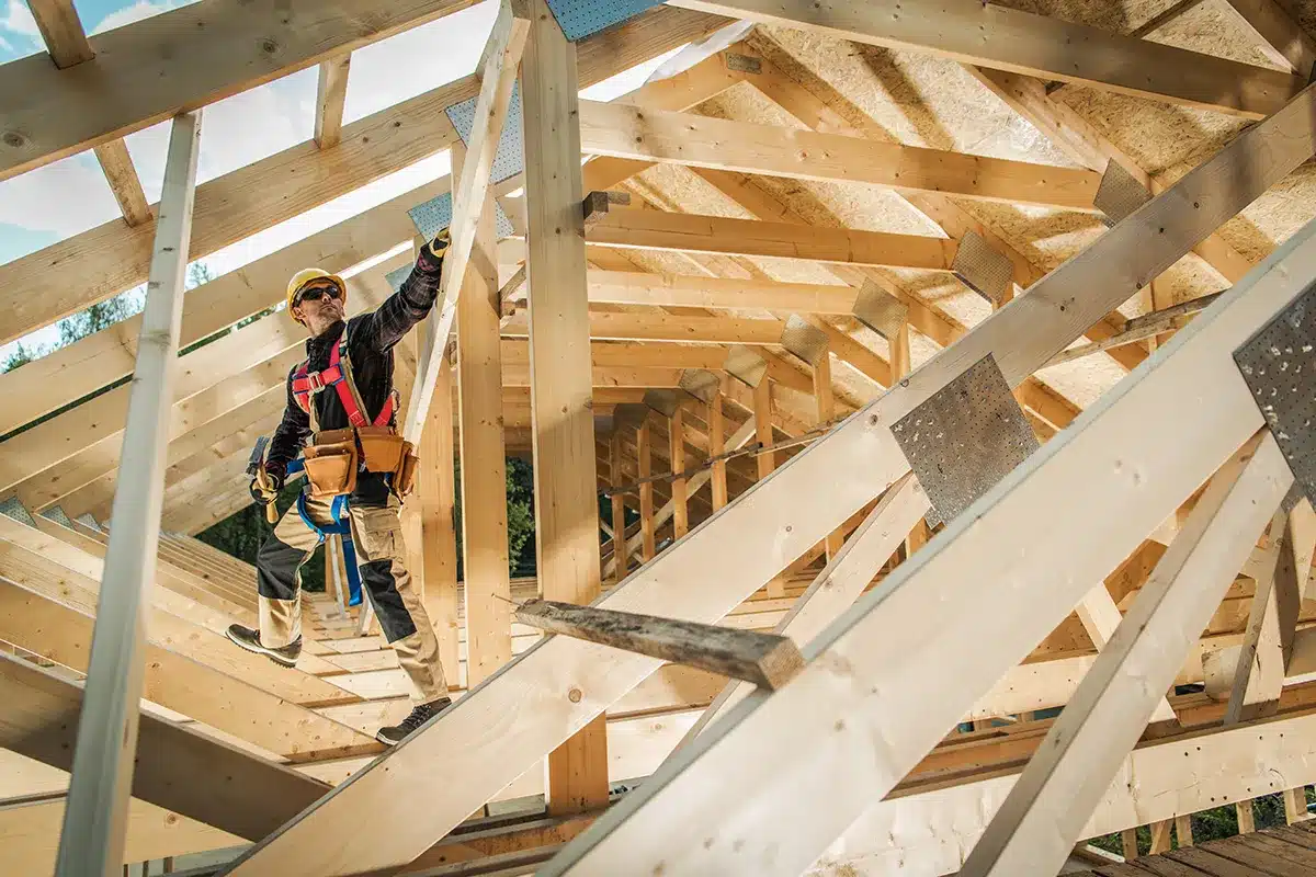 construction worker wearing hard hat while standing in trusses