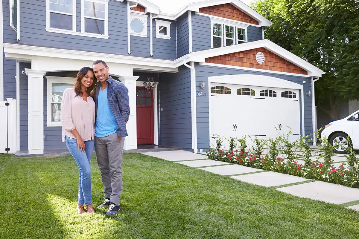 happy-couple-standing-in-front-of-new-house