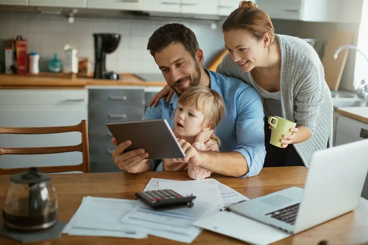 Family looking at tablet with paperwork on table